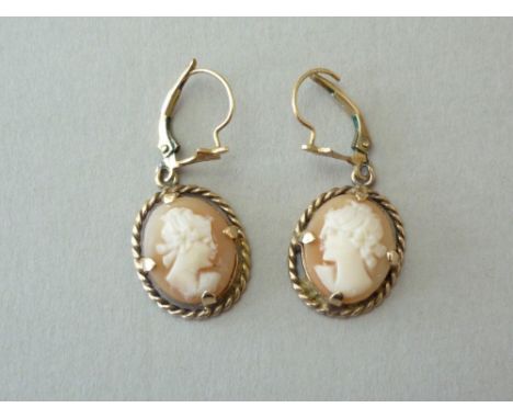 A pair of shell cameo pendant earrings, carved with the profile portrait of a classical lady, claw set within a rope twist fr
