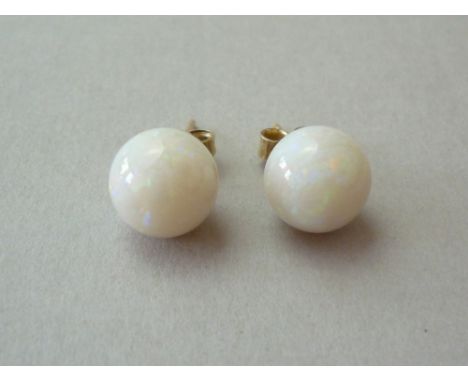 A pair of opal spherical stud earrings, the polished stones measuring approximately 9.6mm diameter, and mounted on yellow met