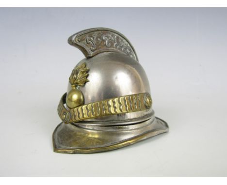 A late 19th / early 20th Century novelty ink well modelled as a combed helmet with grenade badge, in tinplate and brass with 