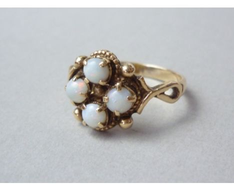 An opal dress ring, the cabochon stones collet and claw set in a quatrefoil arrangement interspersed by pellets, with looping