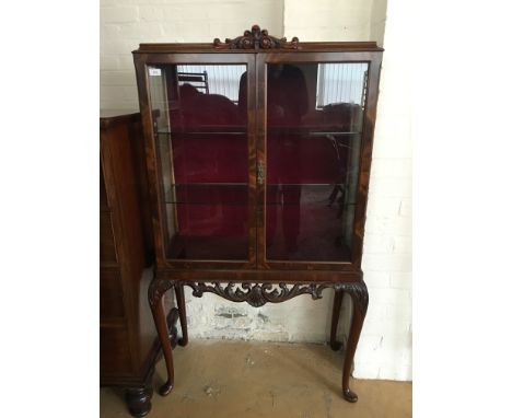 A glazed mahogany vitrine, having a cavetto-moulded caddy top with scroll-carved crest, a pair of glass doors enclosing glass