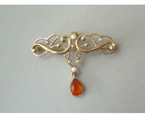 A seed pearl and fire opal openwork pendant brooch, in a scrolling organic design set with seed pearls, above a dependent opa