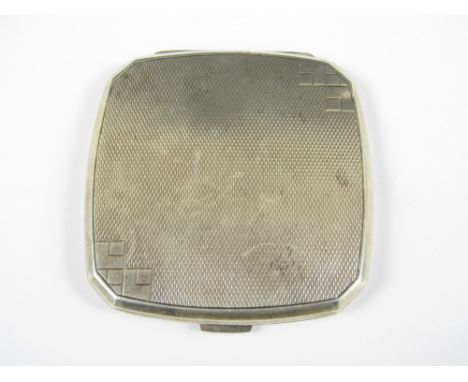 A George V silver powder compact, of cushion form with canted corners, bearing geometric and guilloche engraving to the cover