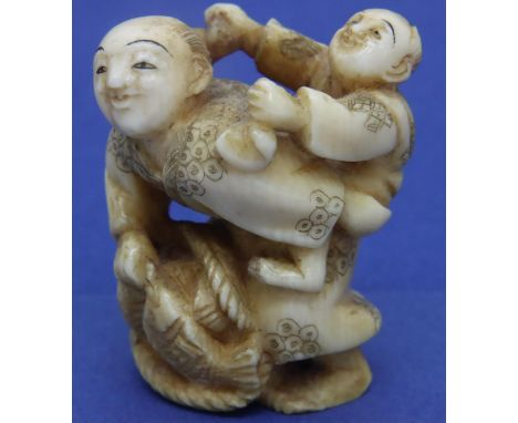 Ivory carved netsuke in the form of a man carrying fish with a boy on his back, H: 38 mm, signed to base. P&amp;P Group 1 (£1