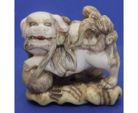 Ivory carved netsuke in the form of a temple dog with his foot on a ball, size 45 mm. unsigned. P&amp;P Group 1 (£14+VAT for 