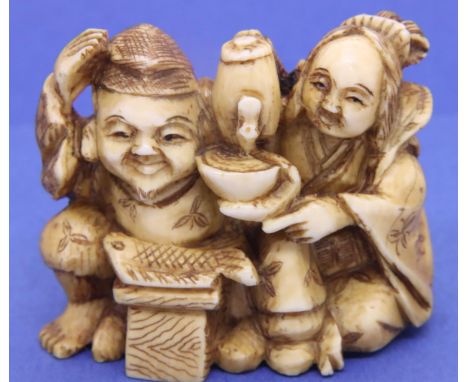 Ivory carved netsuke in the form of a couple, the man with a fish, the woman pouring tea, H: 45 mm, signed to base. P&amp;P G