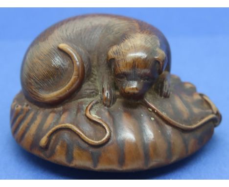 Carved boxwood netsuke in the form of a dog on a cushion playing with a rope, L: 47 mm, unsigned. P&amp;P Group 1 (£14+VAT fo