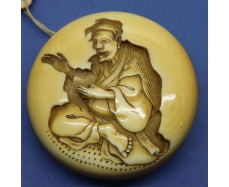 Ivory carved netsuke in circular form showing a seated man, D: 42 mm, signed to back. Small losses to inner rim, otherwise go