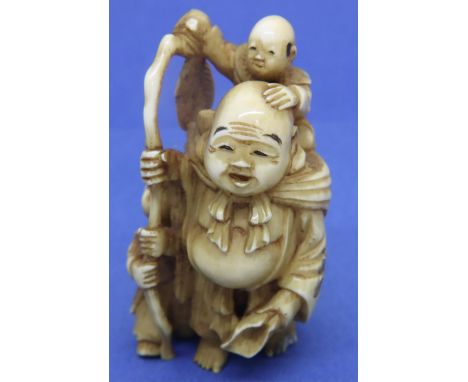 Ivory carved netsuke in the form of a man with a staff with children on his back and to his side, H: 57 mm, signed to base. P