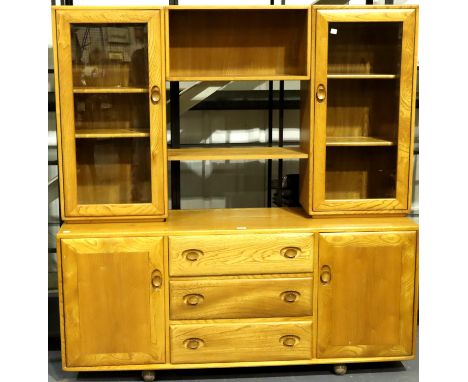 Ercol; a mid 20th century elm cabinet having a sideboard base of cupboards and drawers and glazed cupboards with shelves abov