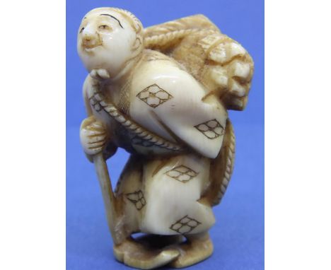 Ivory carved netsuke in the form of a standing man carving wood and holding his hat behind him, H: 44 mm, signed to feet. P&a