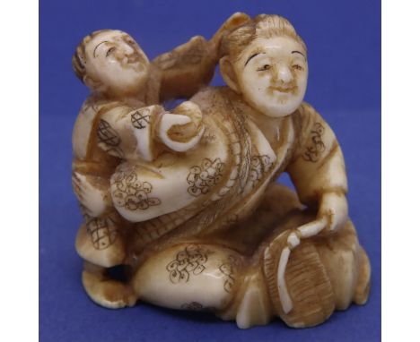 Ivory carved netsuke in the form of a man holding a flail with a boy on his back, H: 41 mm, signed to base. P&amp;P Group 1 (