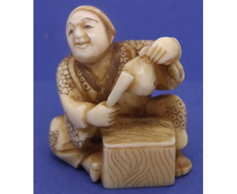 Ivory carved netsuke in the form of a man beating a pouch with a stick, H: 35 mm, signed to base. P&amp;P Group 1 (£14+VAT fo