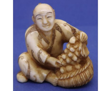 Ivory carved netsuke in the form of a seated man with fruit in a basket, H: 35 mm, signed to base. P&amp;P Group 1 (£14+VAT f