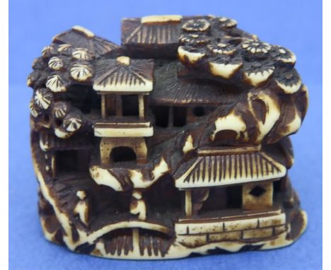 Staghorn carved netsuke in the form of houses with people, animals and foliage, L: 38 mm, signed to base. P&amp;P Group 1 (£1