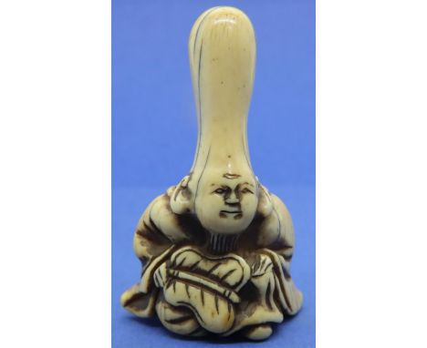 Ivory carved netsuke in the form of a seated God holding a palm leaf, H: 52 mm, unsigned. Age related stained cracks. P&amp;P