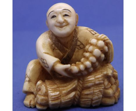 Ivory carved netsuke in the form of a seated street vendor holding maize, H: 35 mm, signed to base. P&amp;P Group 1 (£14+VAT 