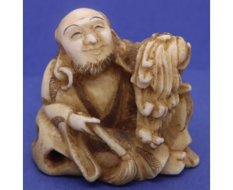 Ivory carved netsuke in the form of a seated street vendor holding a fly whisk, H: 36 mm, signed to base. P&amp;P Group 1 (£1