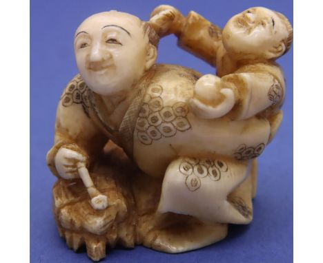 Ivory carved netsuke in the form of a man with a pipe and a boy on his back, H: 35 mm, signed to base. P&amp;P Group 1 (£14+V