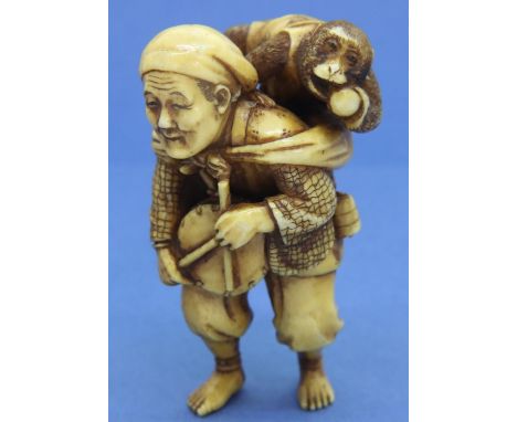 Ivory carved netsuke in the form of a drummer with a monkey on his back, H: 58 mm, signed to back of leg. P&amp;P Group 1 (£1