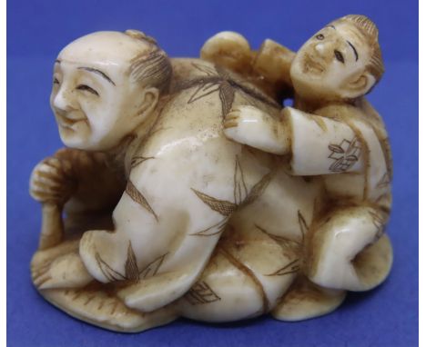 Ivory carved netsuke in the form of a scribe with a boy on his back, H: 30 mm, signed to base. P&amp;P Group 1 (£14+VAT for t