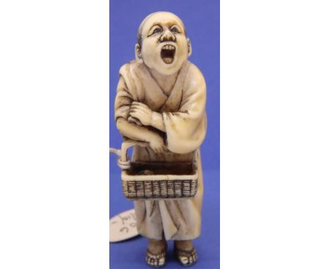 Ivory carved netsuke in the form of a standing street vendor carrying a basket, H: 64 mm, signed to base. P&amp;P Group 1 (£1