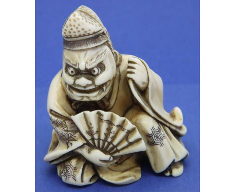 Ivory carved netsuke in the form of a grinning figure holding a fan, H: 48 mm, signed to base. P&amp;P Group 1 (£14+VAT for t