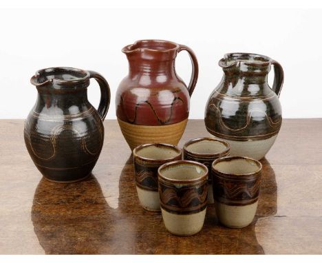 Collection of Winchcombe Pottery consisting of: two large jugs, one with seal mark to the footrim and a set of four tumblers 