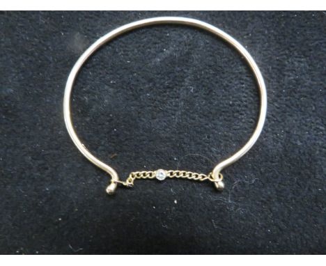 Yellow metal tested for high carat gold bangle, diamond set in the centre of the safety chain Total weight 5.8g