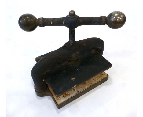 A Cast Iron Book Press with brass finial and 'bulb' handles. Dimensions are 25cm x 30cm with a maximum height of 38cm. Maximu