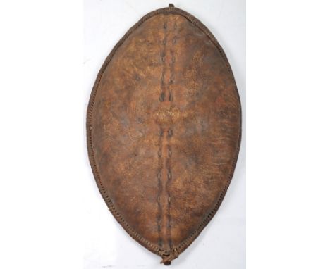 Large Masai Hide Shield of Lenticular Form, the edges bound with leather strips to wooden reinforcements, braced on the insid