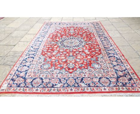 A Persian Isfahan carpet, the central medallion on a red ground, within a multi border, 304 x 211 cm