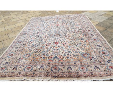 A Persian Kashan carpet, with scrolling floral motifs, on a white ground, within a multi border, 387 x 303 cm