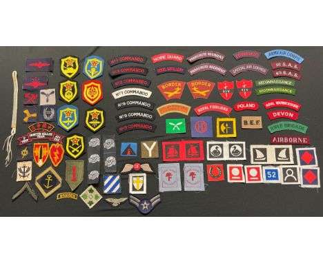 A collection of reproduction British cloth insignia, reproduction Waffen SS deathshead cap insignia and some original post wa