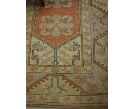 A Turkish style carpet  the central panel set with orange ground lozenge shaped medallion within a stepped cream, orange and 