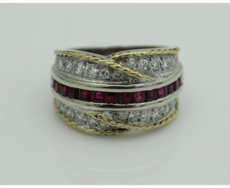 A yellow and white gold (unmarked) dress ring, set with a central row of baguette cut rubies within twenty-six brilliant cut 