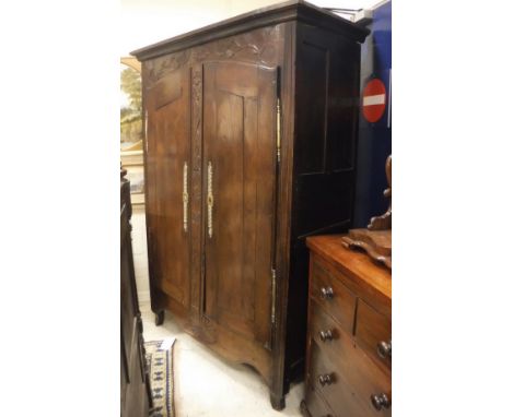 An 18th Century French oak armoire, the moulded cornice above a carved frieze decorated with birds and foliage flanking a sta