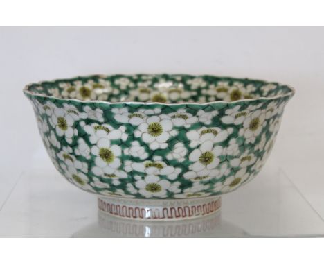 Chinese bowl with lobed rim decorated with prunus flowers on green lattice ground. Painted red seal mark. 22cm diameter.