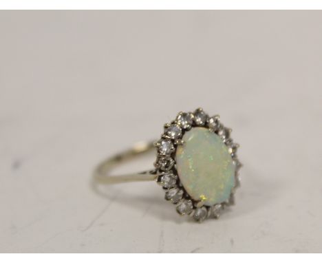 Diamond and opal oval cluster ring with sixteen brilliants in 18ct white gold, 1975. Size 'R 1/2'.