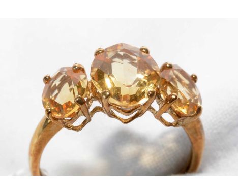 A three-stone citrine ring, of graduated oval facet-cut citrines, on 9ct. yellow gold shank, ring size Q, 2.4grms gross.