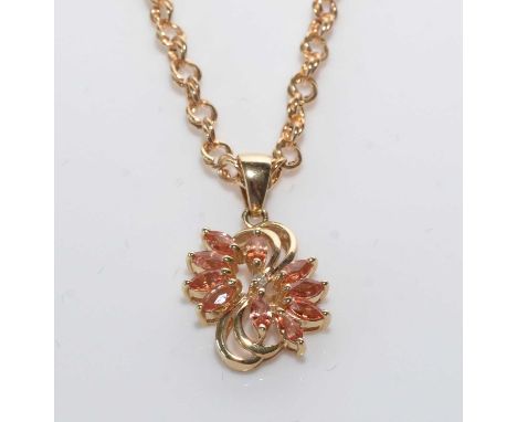 A peach coloured sapphire, diamond and 14ct. yellow gold pendant, the central brilliant-cut diamond surrounded by ten marquis