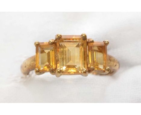 A three-stone citrine ring, the graduated stones rectangular step cut, claw mounted to a 9ct. gold shank, ring size O 1/2.