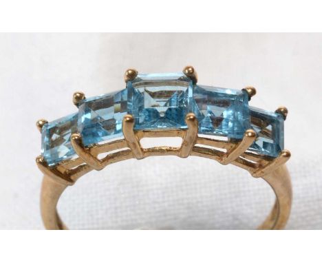 A five-stone blue topaz ring, the graduated square step-cut topaz on 9ct. yellow gold shank, ring size P, 2.4grms gross.