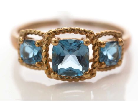 A London blue topaz three-stone ring, with graduated scissor-cut topaz within beadwork mount, on 9ct. yellow gold shank, ring