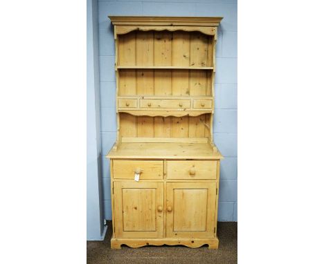 20th Century pine dresser, the projecting cornice above two open shelves, fitted an arrangement of one long drawer and two sh