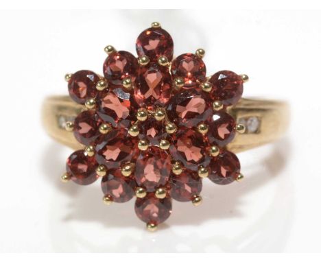 A nineteen-stone garnet cluster ring, set with circular and oval facet-cut garnets flanked by diamond set shoulders, on 9ct. 