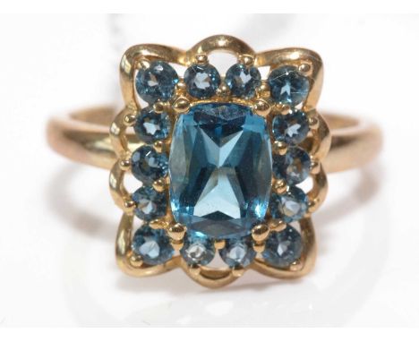 A London blue topaz cluster ring, the central oval scissor-cut topaz surrounded by fourteen circular facet-cut topaz in clust