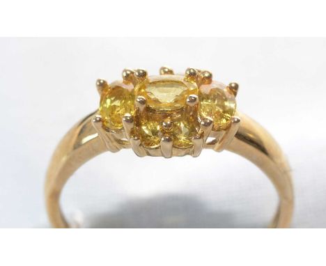 A seven-stone yellow sapphire cluster ring, set with three oval facet-cut yellow sapphires and four circular facet-cut yellow