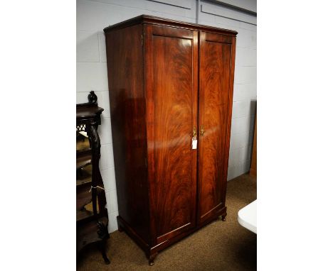 An early 20th Century mahogany two-door wardrobe, the caddy top above a pair of flame mahogany veneered doors, enclosing hang