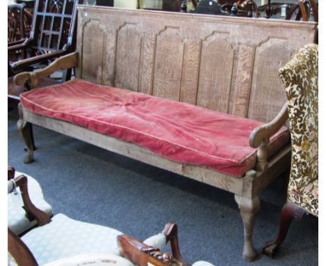 A George III oak arched panel backed open arm settle on cabriole supports, 184cm wide.
